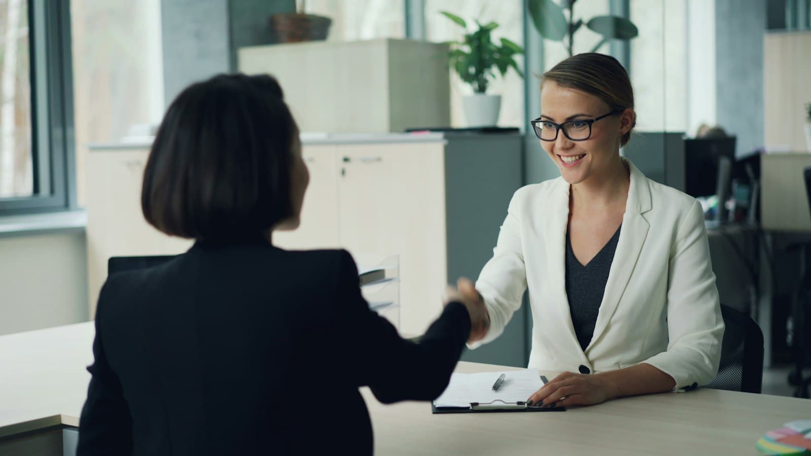 A client shaking hands with an advisor across a desk